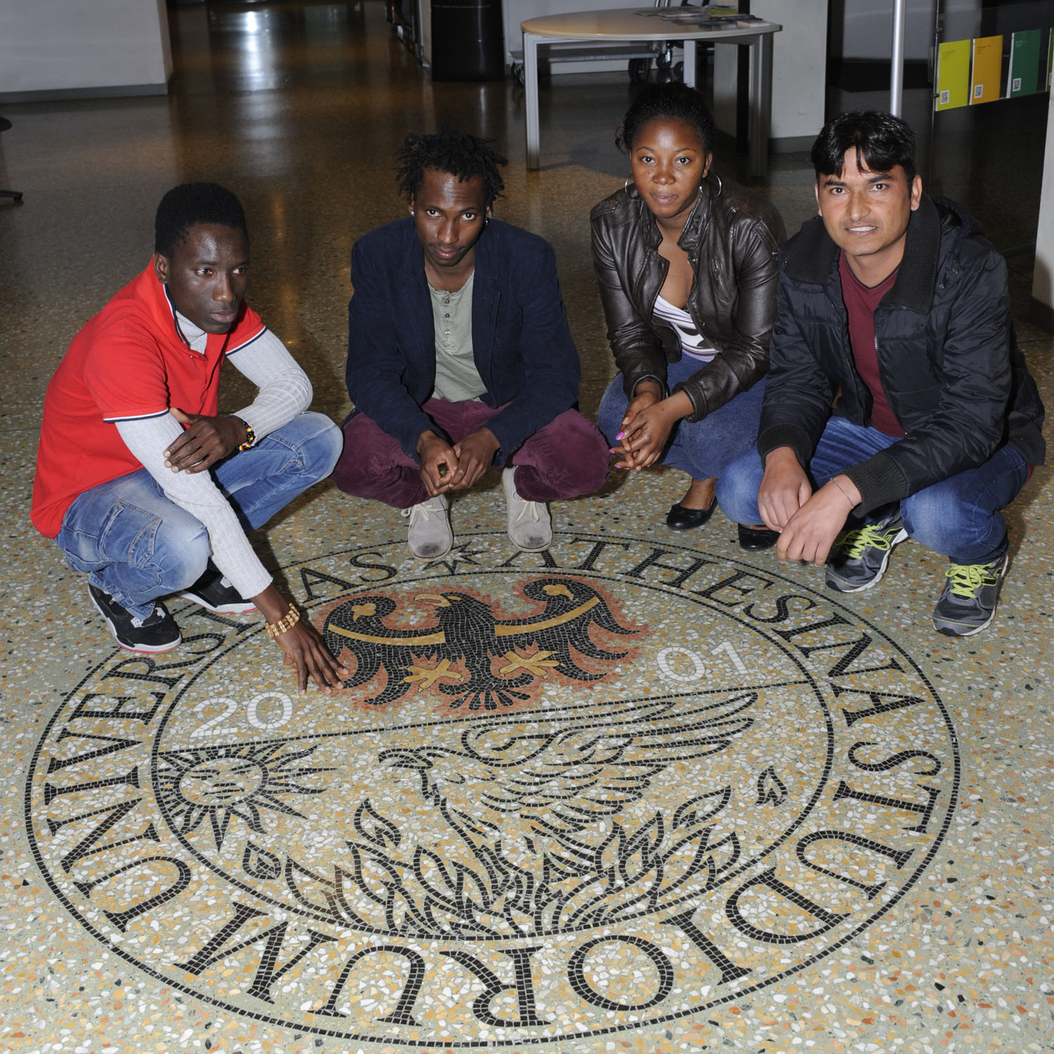 Group of refugees crouched on the unitrento logo on the floor