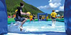 Students playing soap football in a swimming pool, mountains in background