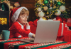 Little boy wearing christmas clothes before a laptop computer
