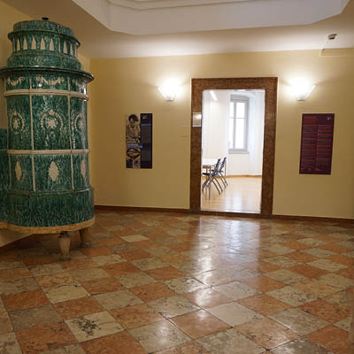 hall with ancient green Tyrolean stove and red marble checkered floor