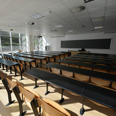 large room with rows of black desks and fixed chairs
