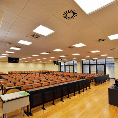 ampia aula con banchi neri e sedie di legno e pavimento giallo
