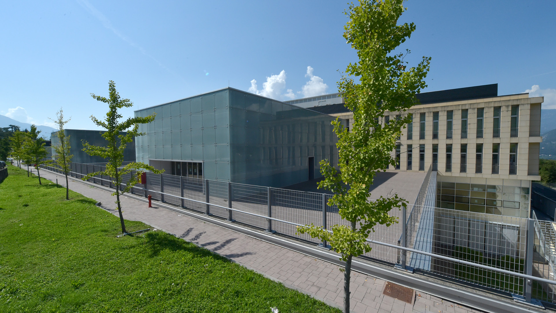 vista dell'edificio in vetro sede del CIBIO presso il Polo tecnologico Fabio Ferrari con prato e arbusti in primo piano