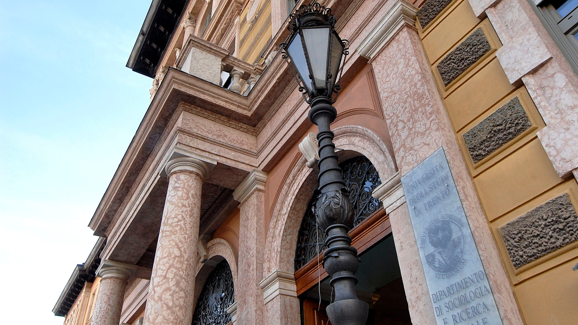 Vista dal basso verso l'alto ingresso Palazzo di Sociologia con targa in vetro e lampione