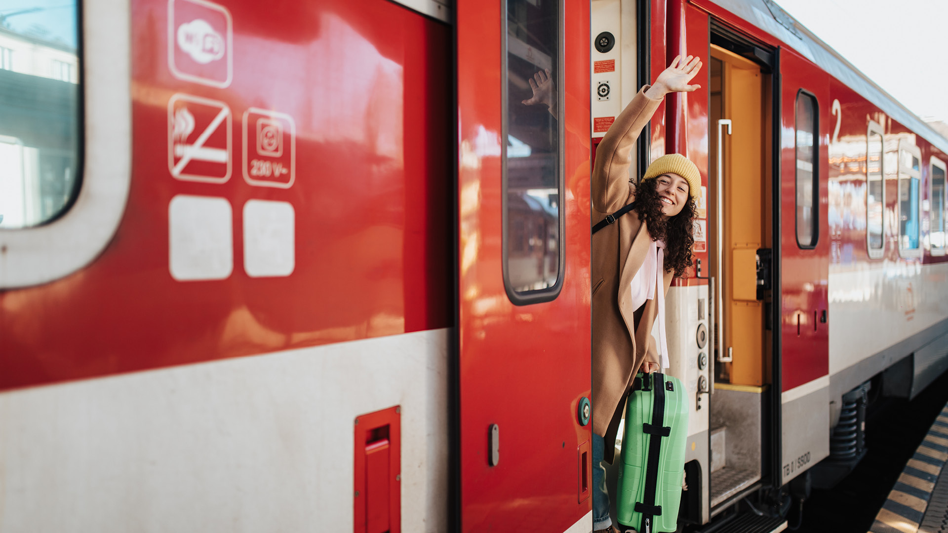 ragazza con trolley che saluta salendo sul treno