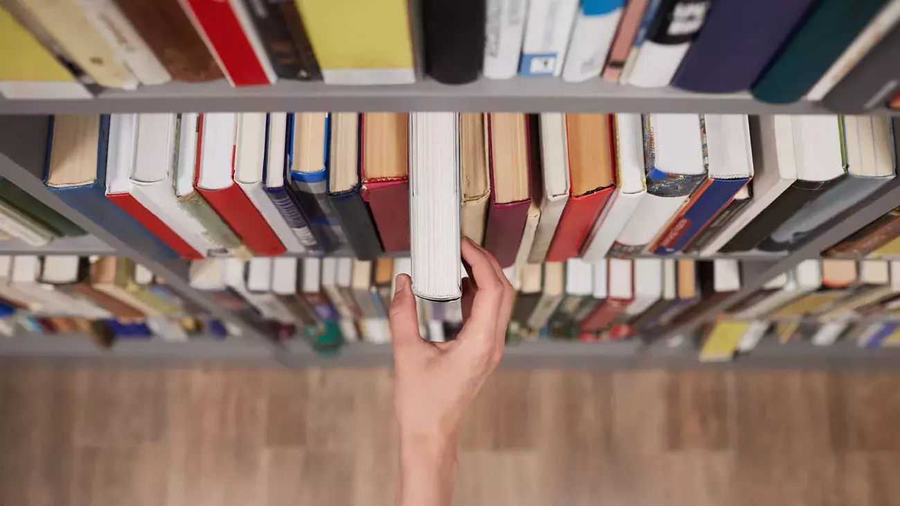 mano che estrae un libro da uno scaffale