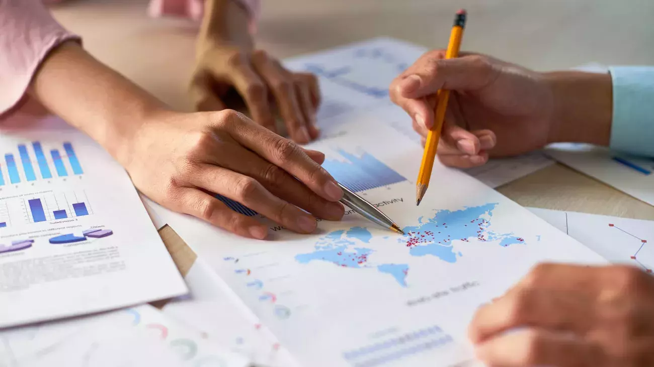 mani di persone che guardano assieme una mappa e segnano con la matita