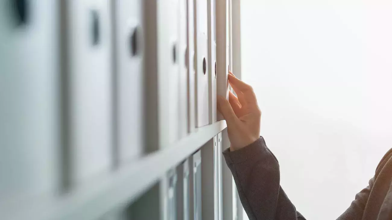 mano che estrae un raccoglitore di archivio da una libreria