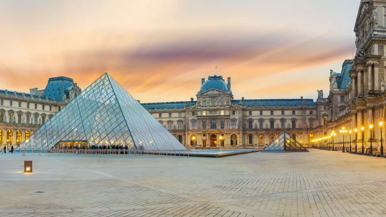 View of famous Louvre Museum with Louvre Pyramid at evening at sunset in Paris France