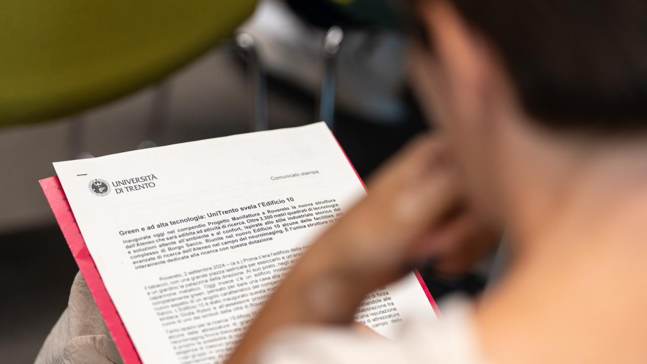 persona di spalle con documento intestato con logo Università di Trento