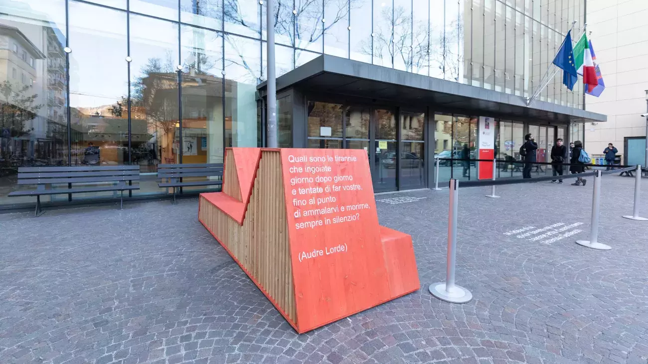 Particolare panchina rossa davanti a Palazzo Prodi, citazione scritta sul legno di Audre Lorde