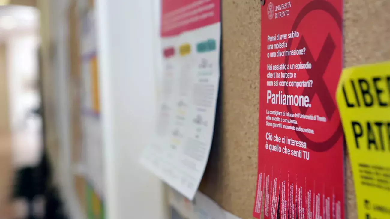 bacheca in sughero su cui è appeso volantino 'Parliamone' con contatti della Consigliera di Fiducia di uniTrento