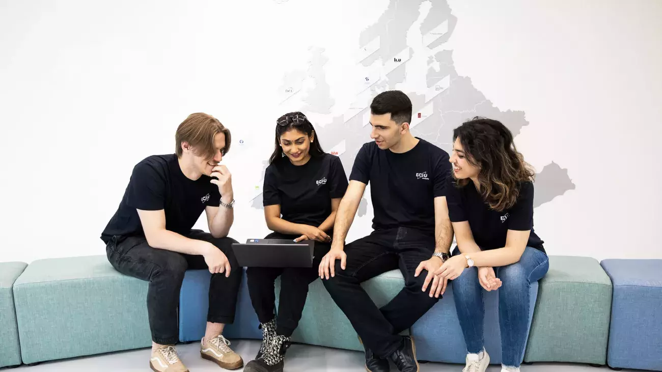 gruppo di ragazzi che collaborano con laptop, sullo sfondo poster eciu