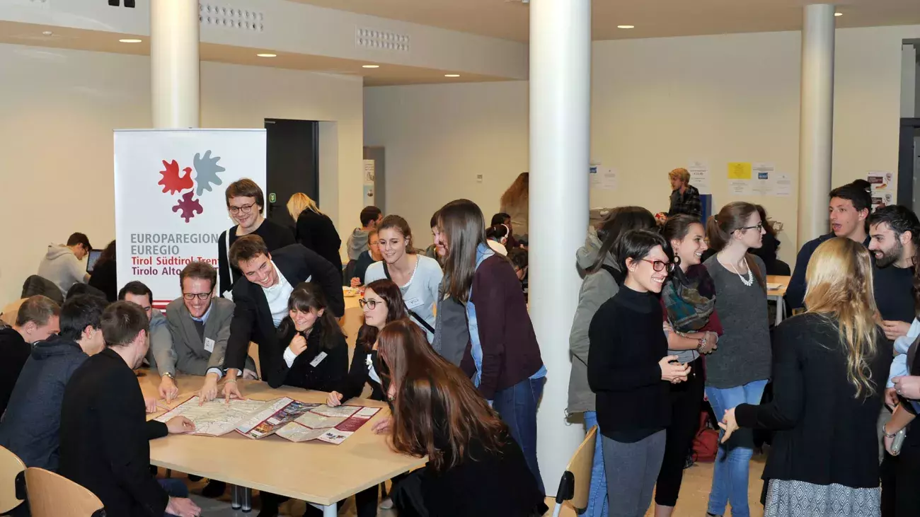 Gruppo di giovani a Palazzo Prodi, manifesto con logo Euregio