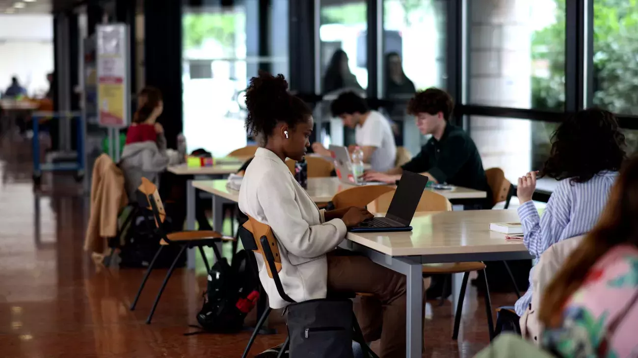 studentessa nel foyer di Giurisprudenza seduta con laptop