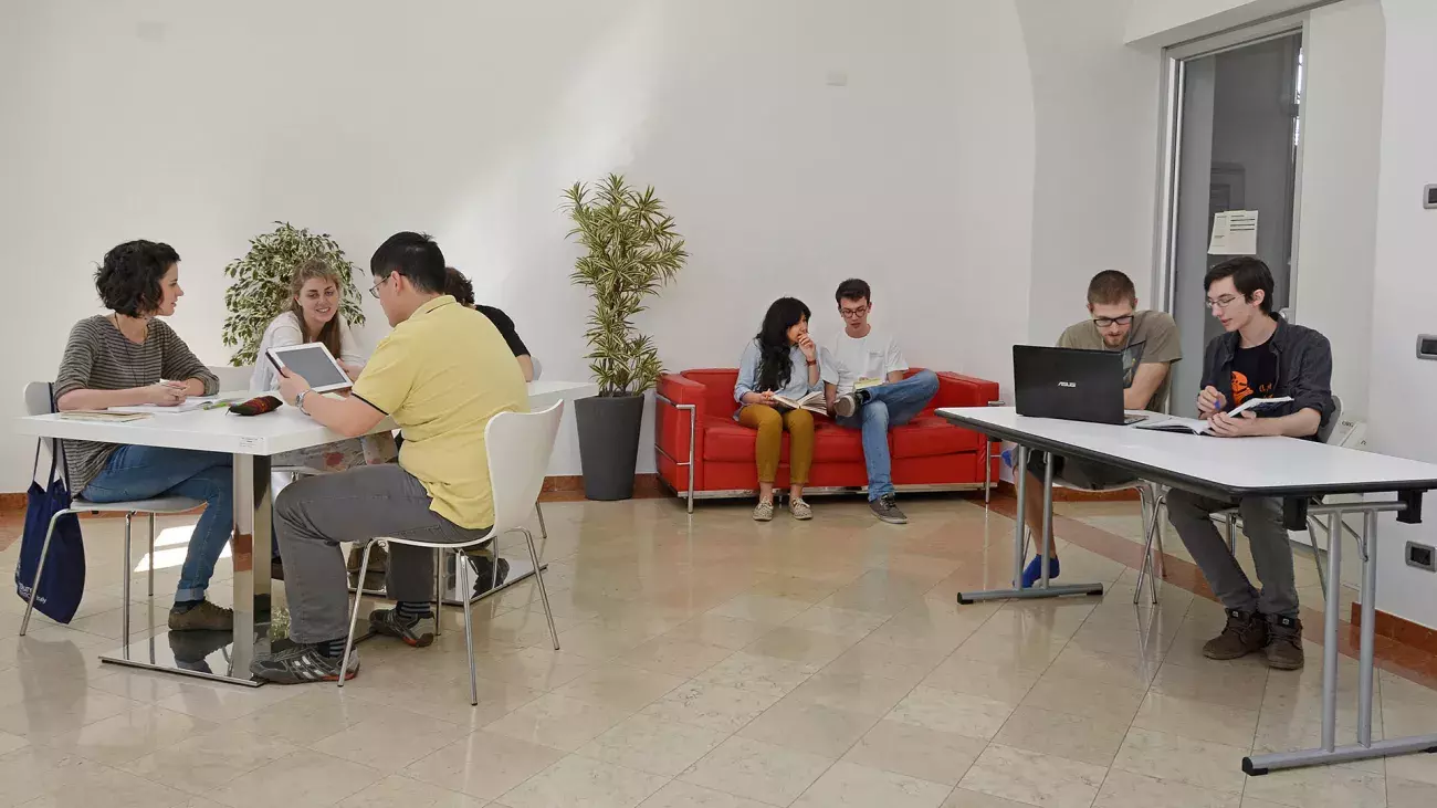 Interni con studenti Collegio Clesio, sala studio con tavoli e divano