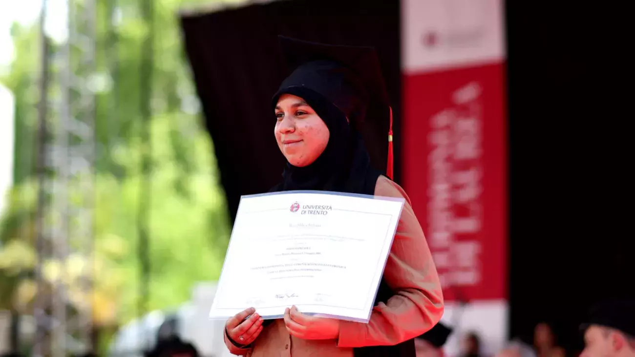ragazza con velo che mostra diploma di laurea