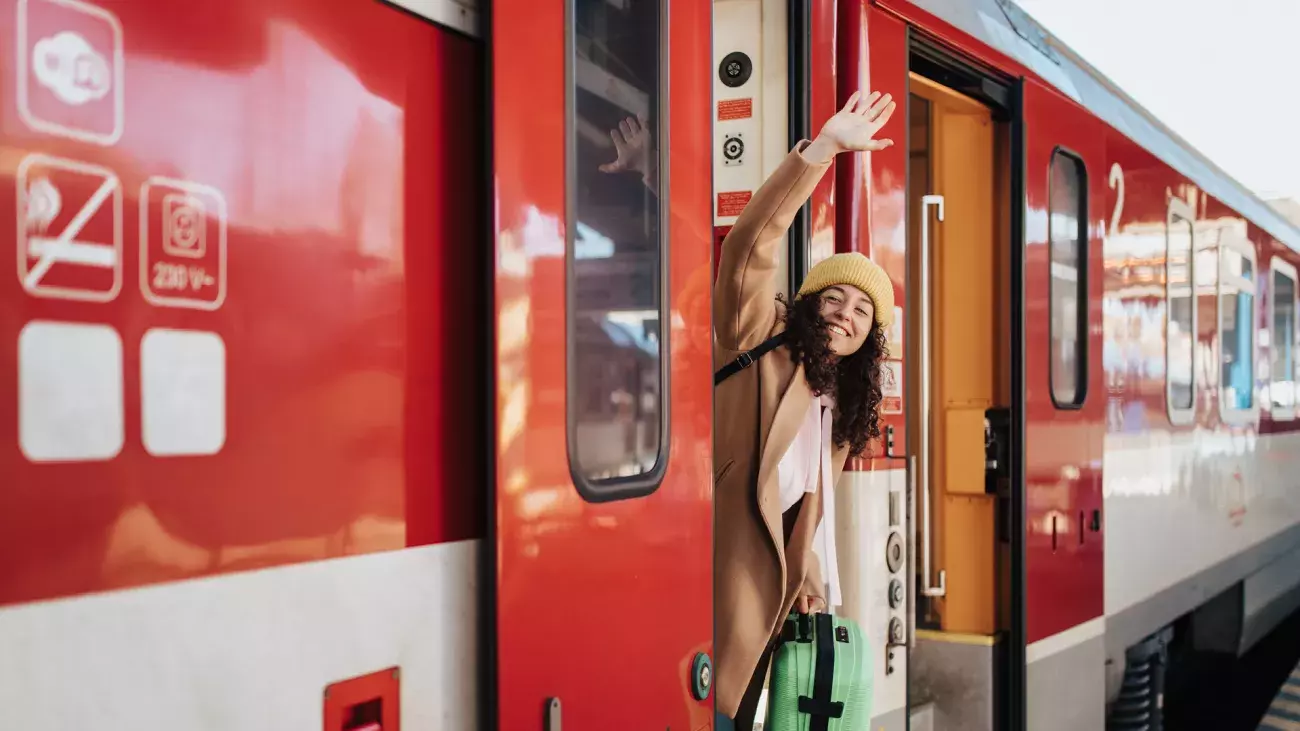 persona che saluta dal vagone del treno in partenza