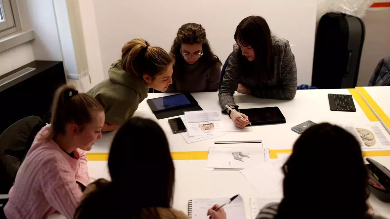 ragazze al tavolo con fogli e dispositivi presso il CISMEd