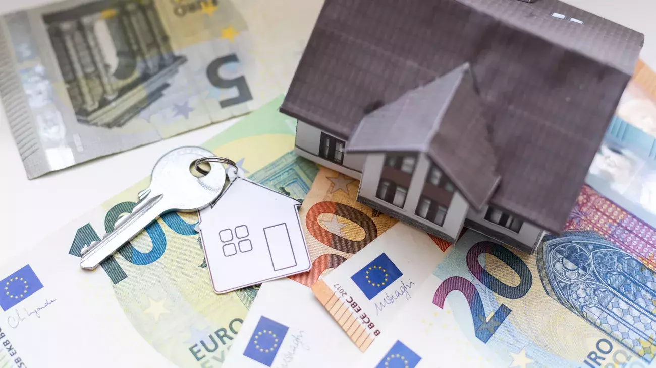 casetta di carta con banconote e chiavi di casa