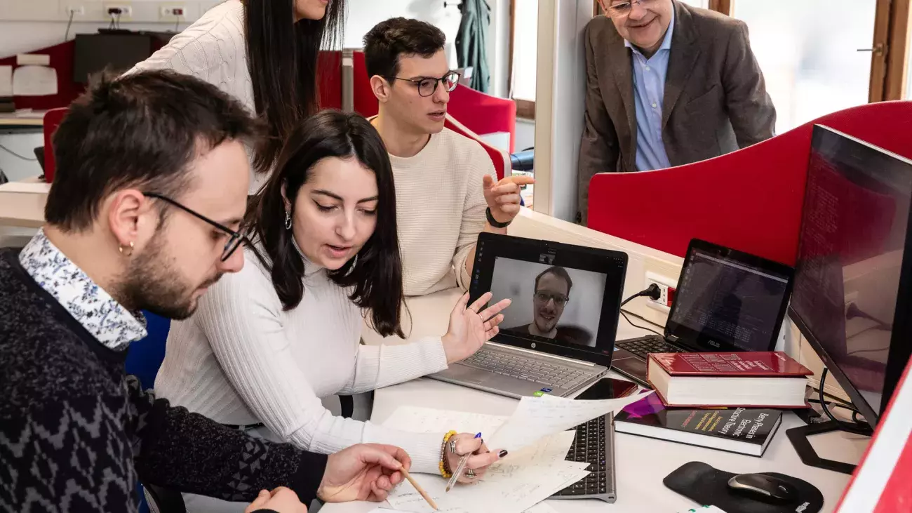 ricercatori che discutono alla scrivania con laptop, libri e documenti