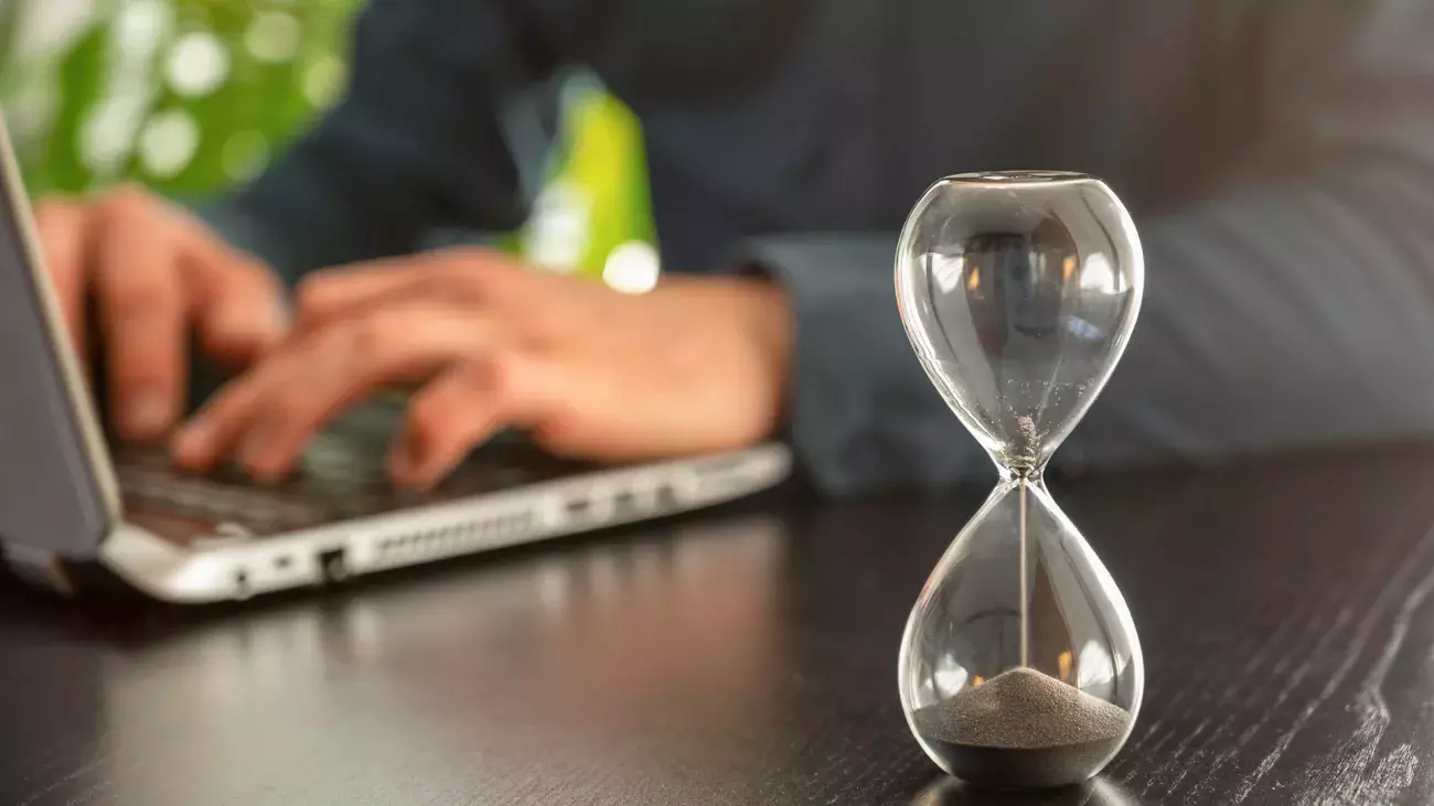 clessidra svuotata, laptop con mani su tastiera