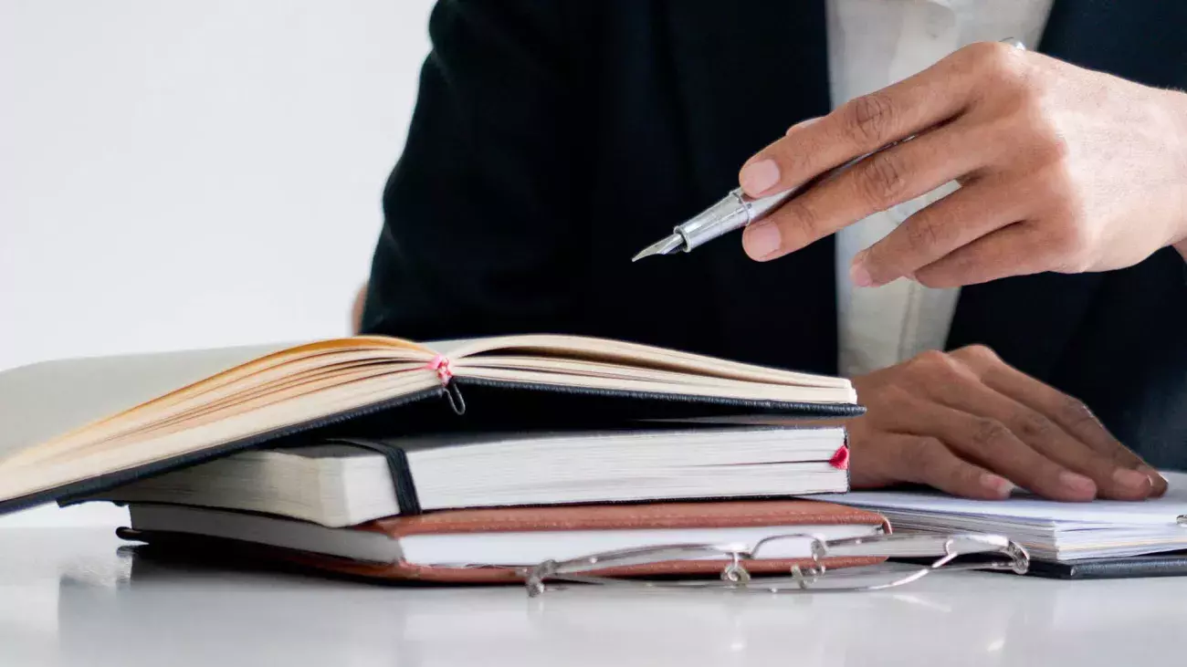 Persona che indica con una penna un taccuino