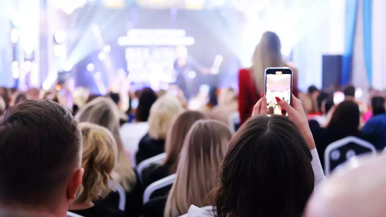 Folla di persone che partecipano a un evento e scattano foto con il cellulare