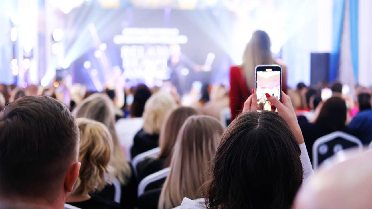 Folla di persone che partecipano a un evento e scattano foto con il cellulare