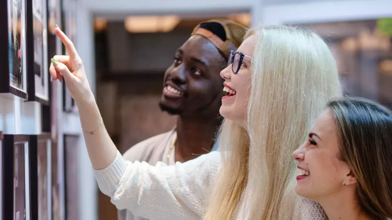 Ragazzi sorridenti che guardano delle foto appese su un muro