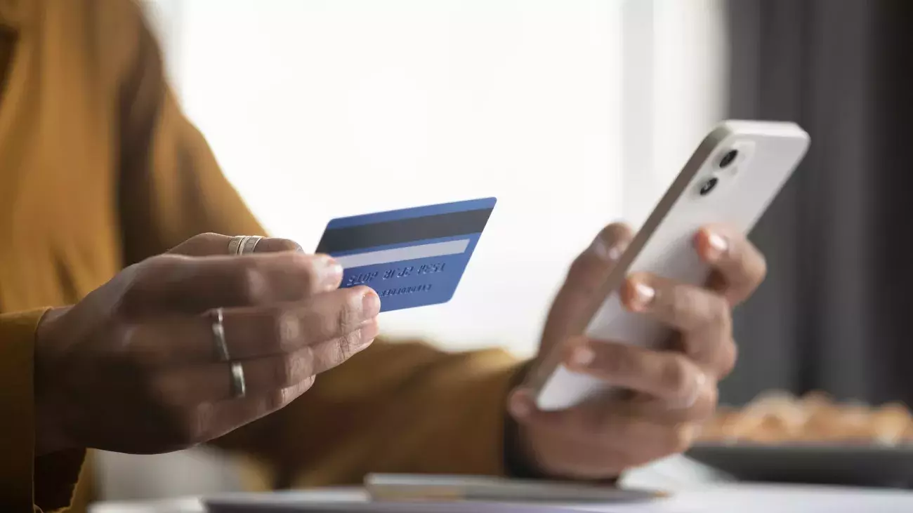 mano con smartphone e carta di credito