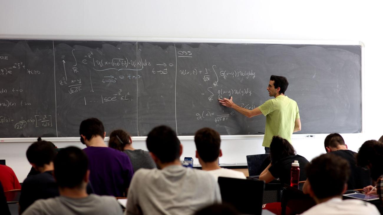 docente che scrive alla lavagna di spalle