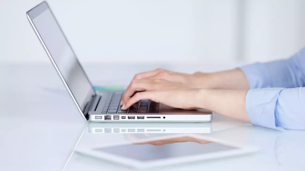 mani che scrivono con laptop