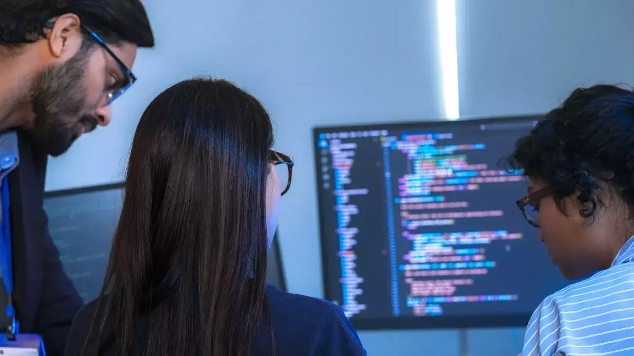 3 ragazzi guardano un computer e fanno programmazione